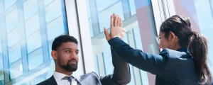 Deux collaborateurs professionnels effectuant un "high five" pour célébrer une réussite après une évaluation des compétences réussie en entreprise.