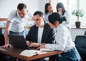 Équipe de professionnels en formation continue collaborant sur un ordinateur portable pour la réussite d'un projet digital.
