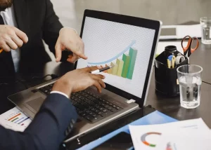 Deux collaborateurs en réunion analysant un graphique de croissance ascendante sur un écran d'ordinateur pour piloter la performance commerciale