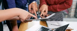 Collaborateurs pointant du doigt l'écran d'une tablette pour valider en équipe un nouvel outil numérique.